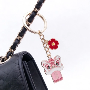 Macro detail of lion dance keychain with Jieyuan characters on a black quilted bag