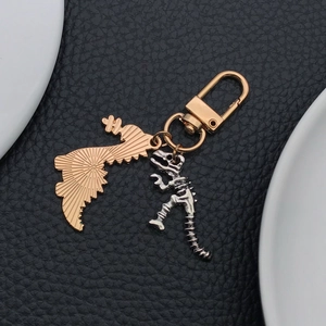Détail d'un squelette de dinosaure et d'un pendentif aile dorée sur un porte-clés métal