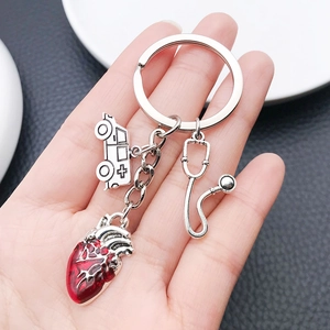 Detail of medical keychain with red heart, white ambulance, and silver stethoscope charm