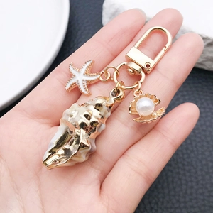 Détail d'un porte-clés marin avec escargot de mer, étoile de mer et breloque en perle