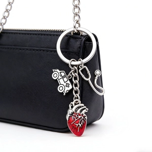 Detailed close-up of stethoscope, red heart, and ambulance charms on a black leather bag