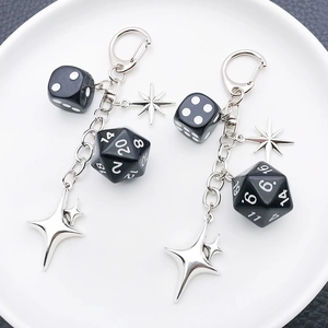 Detail of creative black polyhedral dice keychain with star pendants on a leather texture