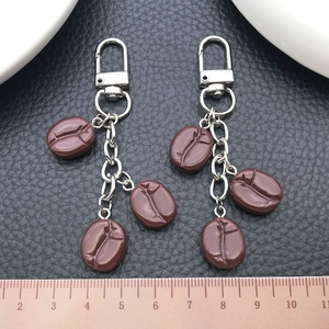 Detailed macro view of 4.5cm resin coffee bean pendants on silver U-shaped metal keychains