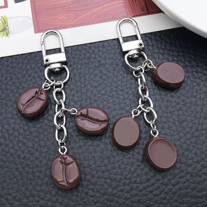 Creative resin coffee bean U-shape keychain with silver metal clip on black leather background