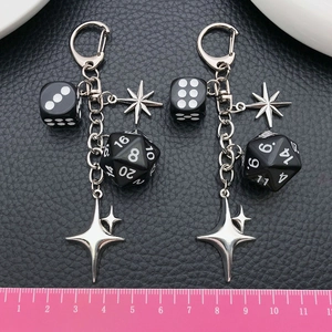 Black dice and star keychain featuring D20 and D6 charms on black leather background