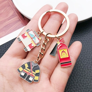 Macro detail of fire extinguisher, engine, and uniform charms on metal keychain