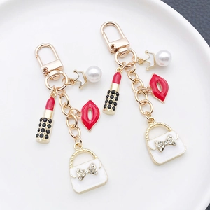 Golden crown lipstick keychain set with white pearl and red lip charms on white tray