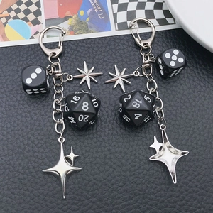 Punk style keychain with black multi-sided dice and silver star charms on leather background