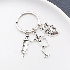 Detailed close-up of antique silver medical keychain with heart, stethoscope and syringe charm