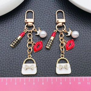 Detailed view of white pearl with crown and charms on a gold-tone metal keychain