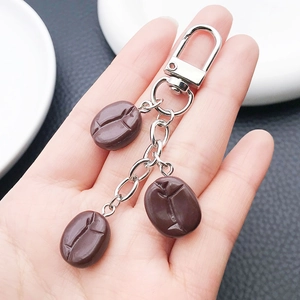 Detail of three realistic resin coffee bean pendants on a silver lobster clasp keychain