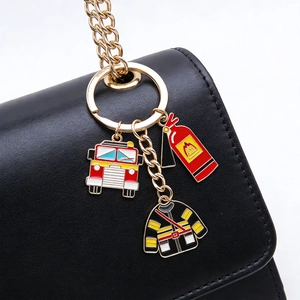 Detail of firefighter keychain with red fire truck and extinguisher charms on black leather bag