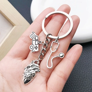 Detailed close-up of antique silver stethoscope and heart charms on a metal keychain