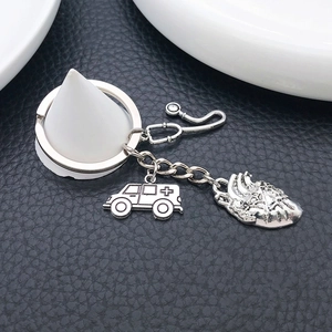 Antique silver medical keychain with stethoscope heart and ambulance charms on a black background