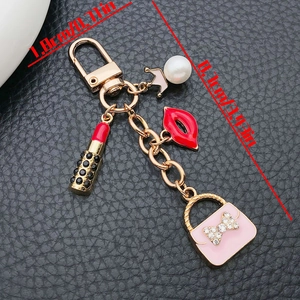 Vue détaillée du porte-clés doré avec charms sac à main rose et rouge à lèvres
