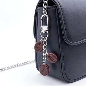 Detail of coffee bean pendants on a black leather bag with silver chain