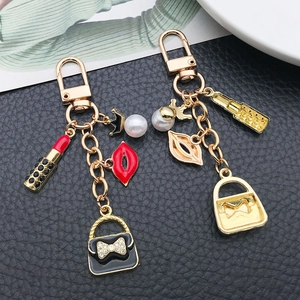 Porte-clés doré avec charms de rouge à lèvres et sac à main sur cuir noir