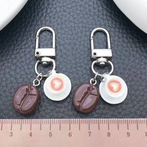 Detail of creative resin coffee bean and heart latte art cup keychains on black leather