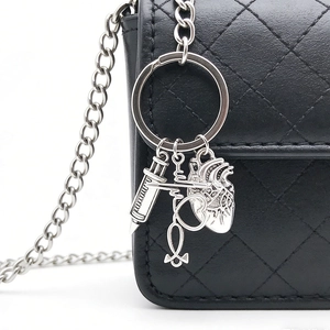 Detailed close-up of a silver medical syringe and heart stethoscope keychain on a bag