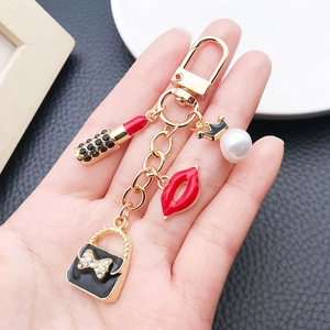 Vue détaillée du porte-clés doré avec charms rouge à lèvres, sac à main et perle