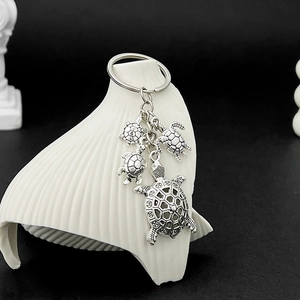 Detail showing vintage silver turtle charms with intricate geometric patterns on metal keychain