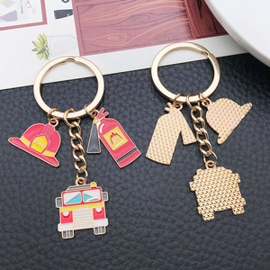 Firefighter keychain with red helmet, extinguisher, and fire truck charms on gold ring