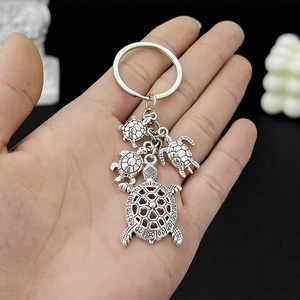 Close-up of antique silver turtle keychain with one large and three small metal charms
