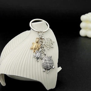 Detailed close-up of antique silver and gold turtle charms on a metal keychain ring
