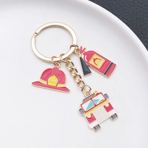 Macro view of fire safety keychain with helmet extinguisher and truck charms on a ceramic plate
