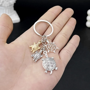 Detailed close-up of multi-pendant turtle keychain in gold and silver metal finishes