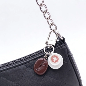 Detail of coffee bean and heart latte art charms on black quilted handbag chain