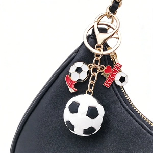 3D soccer ball keychain with red shoe charm on a black textured bag close-up