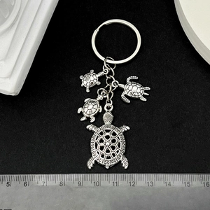 Antique silver sea turtle keychain with multiple alloy charms on black background