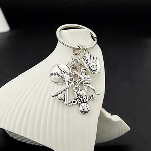 Detail of silver softball keychain with bat, glove, and heart charm on dark background