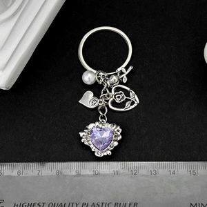 Porte-clés argenté antique avec cristal de cœur violet et breloques roses sur fond noir