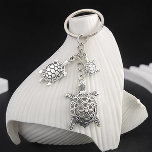 Macro detail of antique silver turtle keychain featuring intricate shell textures on a shell