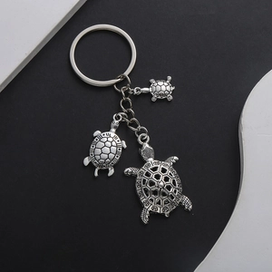Vintage silver sea turtle keychain with three detailed metal pendants on a ring