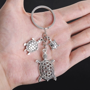 Detailed close-up of three vintage silver-plated turtle pendants on a metal keychain