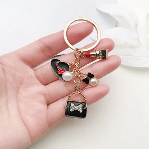 Porte-clés doré élégant avec sac à main noir, nœud papillon et breloques en perles