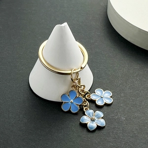 Détail des breloques fleurs de cerisier en émail bleu sur un porte-clés doré