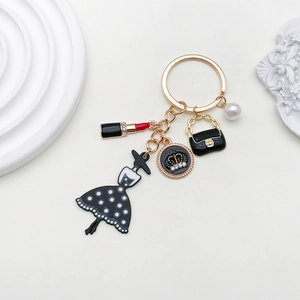 Close-up of golden fashion keychain with dress, lipstick, handbag and pearl charms