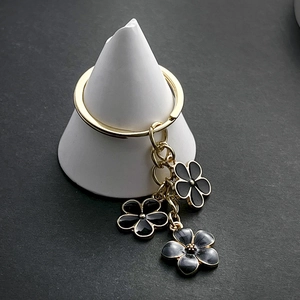 Détail d'un porte-clés doré avec trois pendentifs fleurs de cerisier en émail noir
