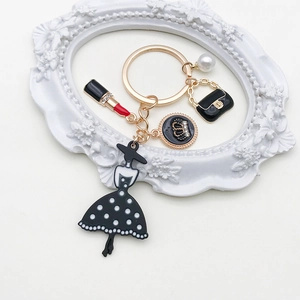 Detail view of gold fashion keychain with elegant black dress and pearl charms