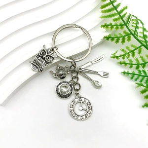 Detailed view of metal keychain with tea time pot, owl, clock, and cutlery charms