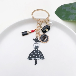 Detailed close-up of a gold alloy keychain with lipstick and handbag charms on a white plate
