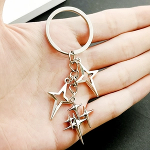Detail showing multiple silver star charms on a metal keychain held by a hand