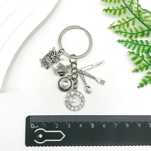 Vintage Alice in Wonderland tea set keychain with owl and clock charms on white background