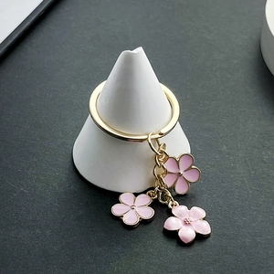 Détail de breloques cerisier en émail rose avec chaîne et anneau en métal doré