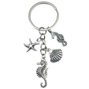 Silver metal marine keychain with seahorse, starfish and scallop shell pendants on white background