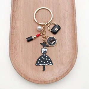 Detail of fashion keychain with black dress, pearl, lipstick and gold charms